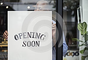 Man putting on store opening soon sign