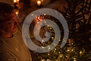 Man putting string lights on a Christmas tree