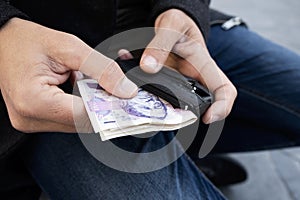 Man putting in or taking off money from his wallet