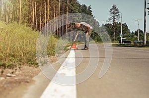 Man putting triangle warning caution sign on road side