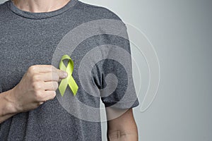 Man putting turquoise or teal ribbon on his shirt. Awareness symbol photo