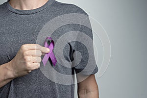 Man putting violet purple ribbon on his shirt. Awareness symbol