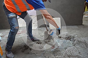 man putting water and making concrete mix to glue cement blocks and elucidate, photo