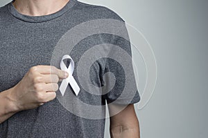 Man putting white ribbon on his shirt. Awareness symbol