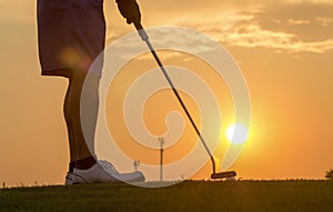 Man puttinging golf against sunset