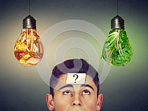 Man with question looking at junk food vegetables light bulbs
