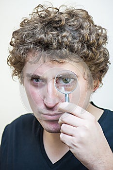 Man questionably looking through magnifying glass