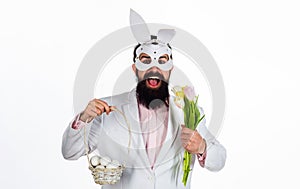 Man in rabbit mask with Easter basket eggs and flowers.