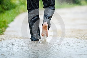 A man in the rain is barefoot in puddles