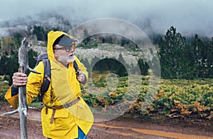 Man in raincoat and backpack on rainy day in mountains