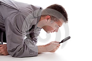 Man with raincoat is looking with magnifying glass