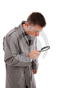 Man with raincoat is looking with magnifying glass
