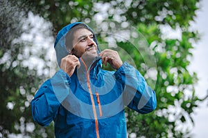 man in a raincoat in the rain in a rainy day in the park, the concept of the rainy season