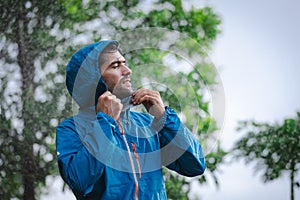 man in a raincoat in the rain in a rainy day in the park, the concept of the rainy season