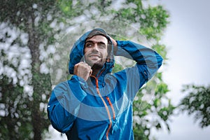 man in a raincoat in the rain in a rainy day in the park, the concept of the rainy season