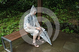 Man in raincoat sitting alone on the bench