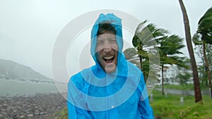 A man in a raincoat is under a hevy rain and stormy wind. Shot on an action camera. Tropical storm concept. Contains