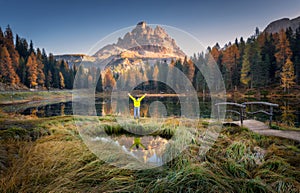 Man with raised up arms on Antorno lake in autumn at sunrise photo