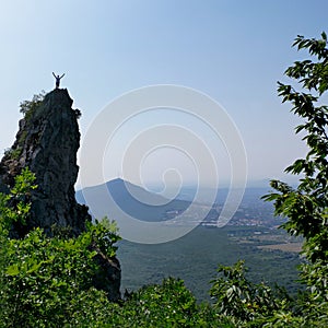 Man raises his hands up on top of rock