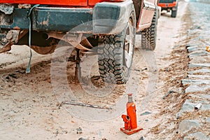 A man raises on a jack 4x4 off road truck