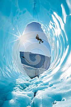 Man rappelling into entrance of glacier ice cave in the mountains of Alaska