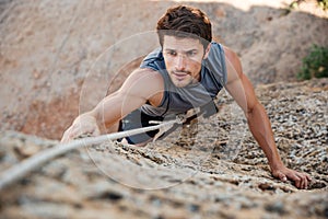 Man reaching for a grip while he rock climbs