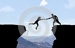 Man reaching hand to woman jumping over abyss.