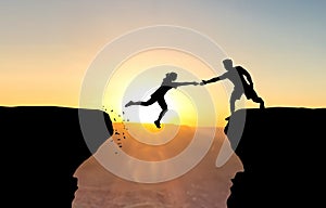 Man reaching hand to woman jumping over abyss. photo