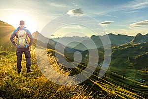 Man reaching summit enjoying freedom. Beautiful sunrise and layered mountain silhouettes in early morning. Lechtal and