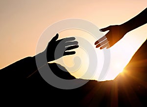 Man reaching for woman`s hand at sunset. Help concept