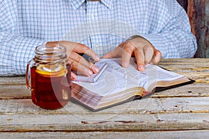Man reading the Bible as well as tea on the table