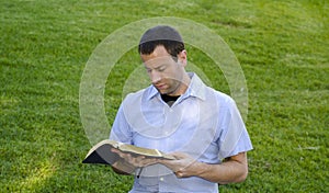 Man reading Bible in the grass.