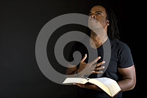 Man reading a bible isolated on black.