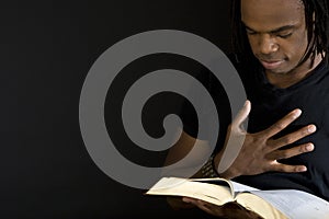 Man reading a bible isolated on black.