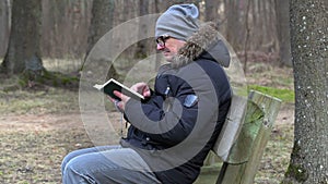 Man reading Bible and praying on bench in the park