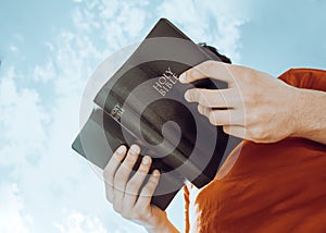 Man reading Bible on sky background