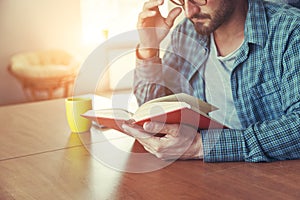 man reading book with cup of tea or coffee