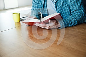 man reading book with cup of tea or coffee