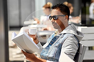 Man reading book and drinking coffee at city cafe