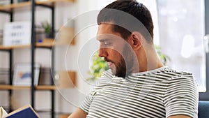 Man reading book and drinking coffee at home