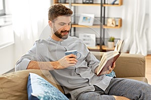 Man reading book and drinking coffee at home