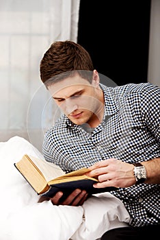 Man reading a book in his bed.