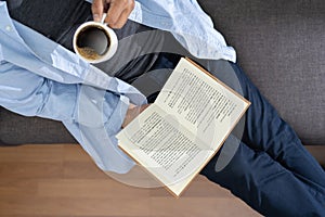 Man reading a book and holding cup of coffee Sit Read Knowledge