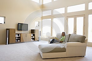 Man reading book in living room smiling