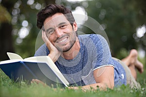 man reading book while lying on grass