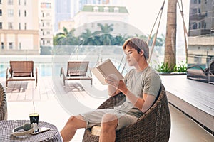 Man reading book near swimming pool. Relax concept