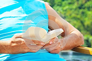 Man reading book poolside