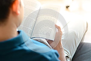 A man reading book while sitting on the couch