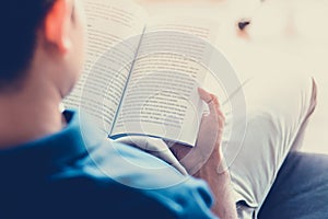 Man reading book while sitting on the couch - vintage tone