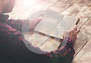 Man reading book sitting at a wooden table